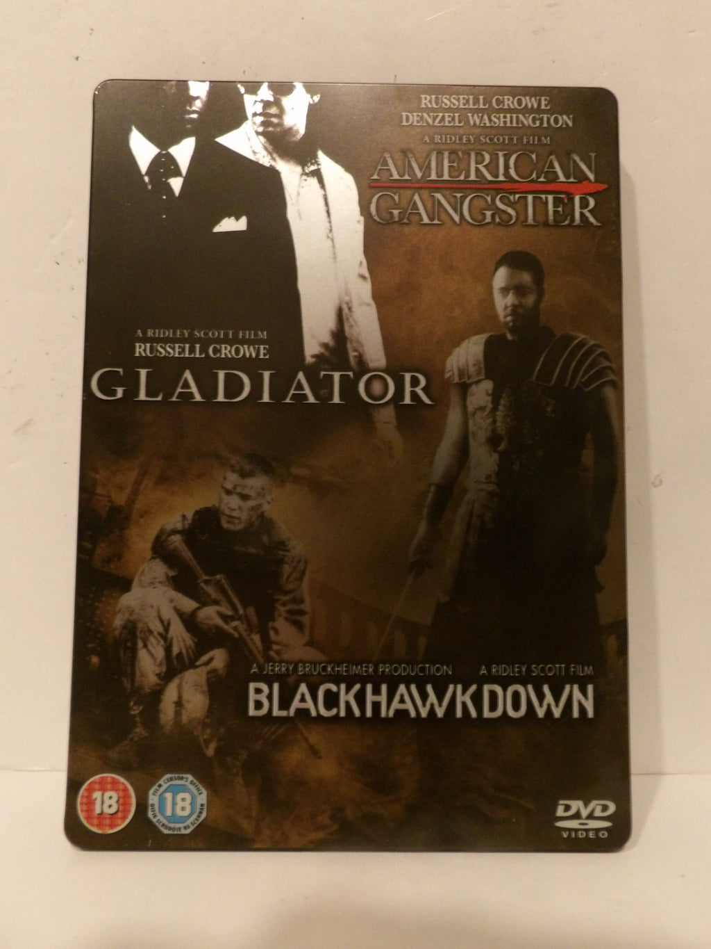 A DVD cover for the movie Black Hawk Down, featuring Russell Crowe and Denzel Washington. The cover has a dark, sepia-toned design with images of the actors in costume and the movie title 'Black Hawk Down' in white text at the bottom.