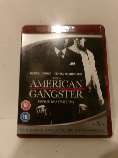 A boxed movie case for 'American Gangster' with Russell Crowe and Denzel Washington, photographed against a plain off-white background. The cover is mostly black and white with red accents, and age rating badges are visible on the lower left.