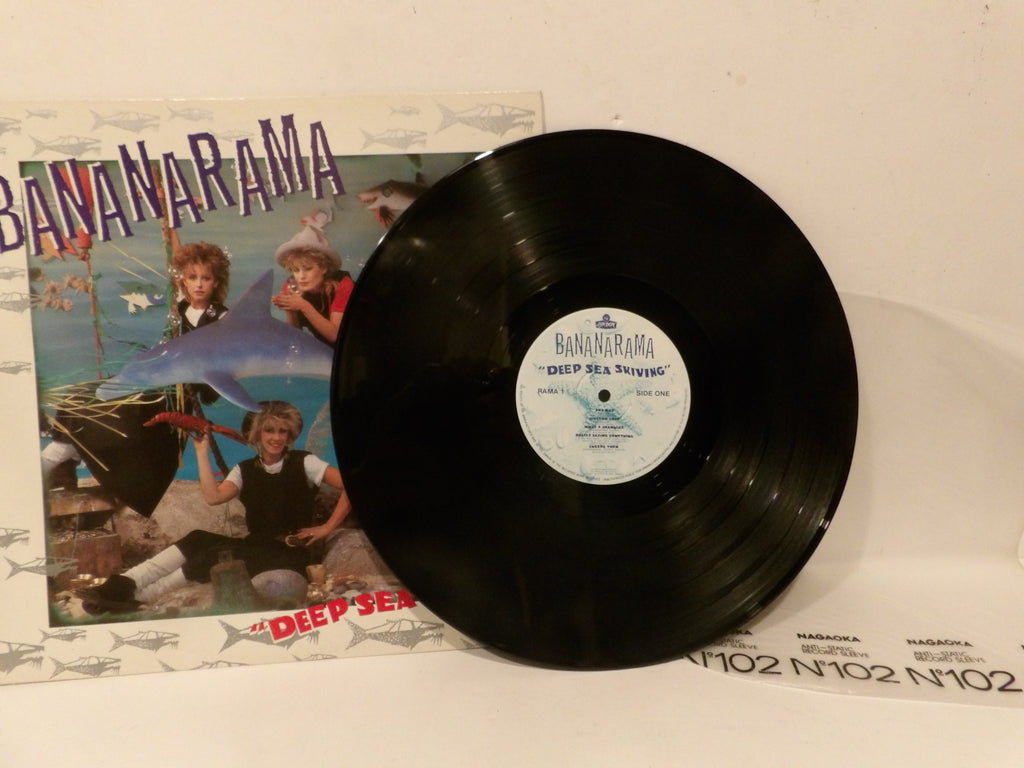 A black vinyl record partially covering its printed album cover, with the visible text and artwork for Bananaama's "Deep Sea Driving.".
