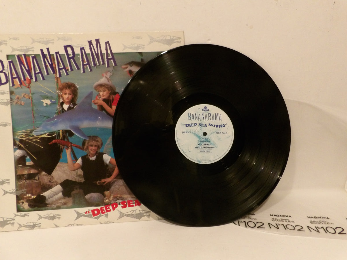 A black vinyl record partially covering its printed album cover, with the visible text and artwork for Bananaama's "Deep Sea Driving.".