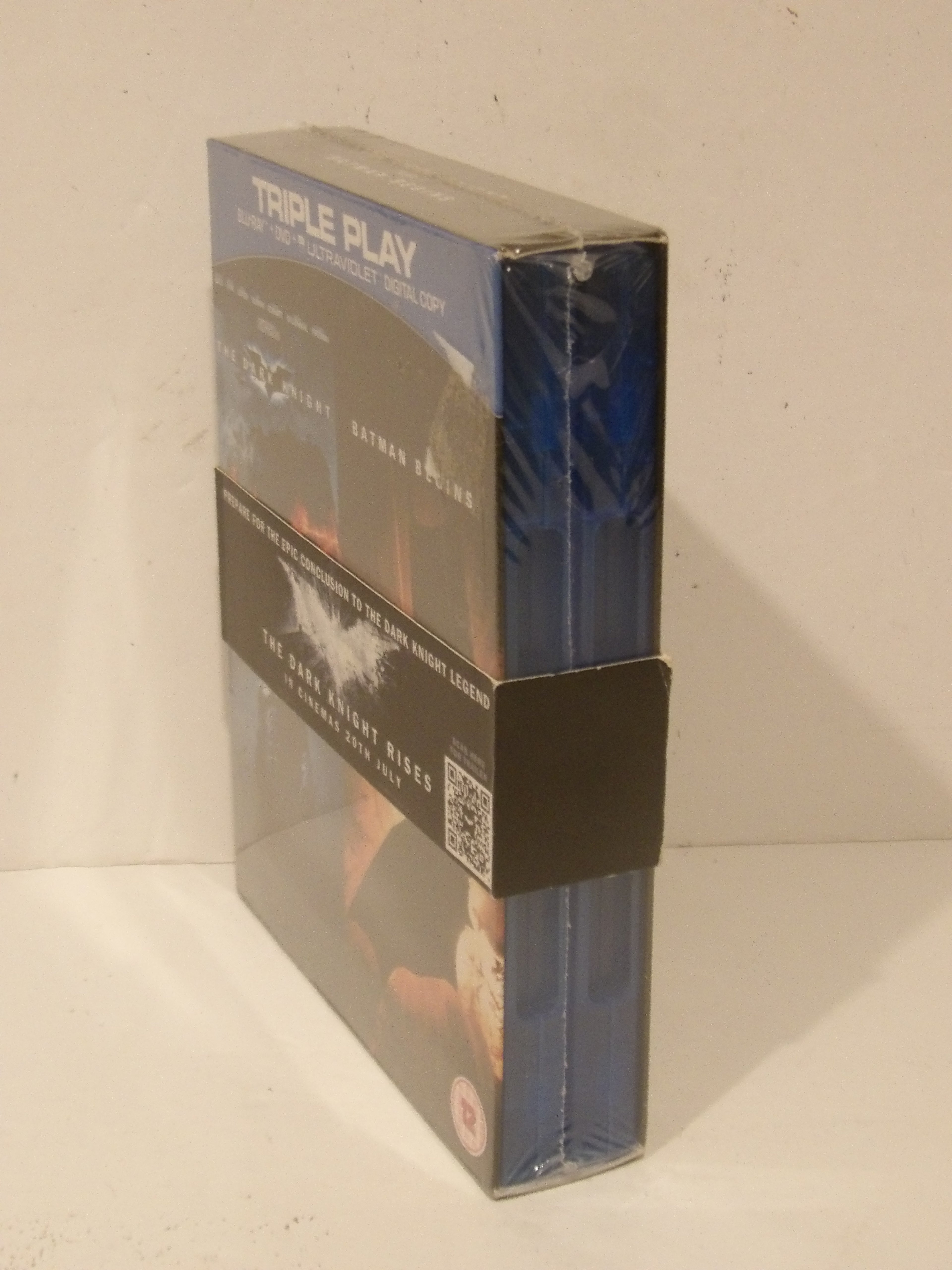 A boxed movie collection titled 'TRIPLE PLAY' in a shrink-wrapped plastic case, standing upright against a plain off-white wall. The packaging shows dark blue and black design elements with movie imagery and text.