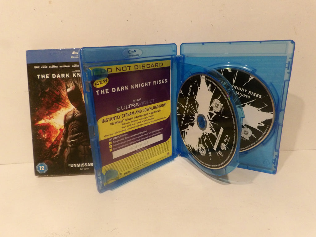 A Blu-ray box set for The Dark Knight Rises, showing the front cover, a blue plastic case with a 'Do Not Discard' insert, and two Blu-ray discs inside.
