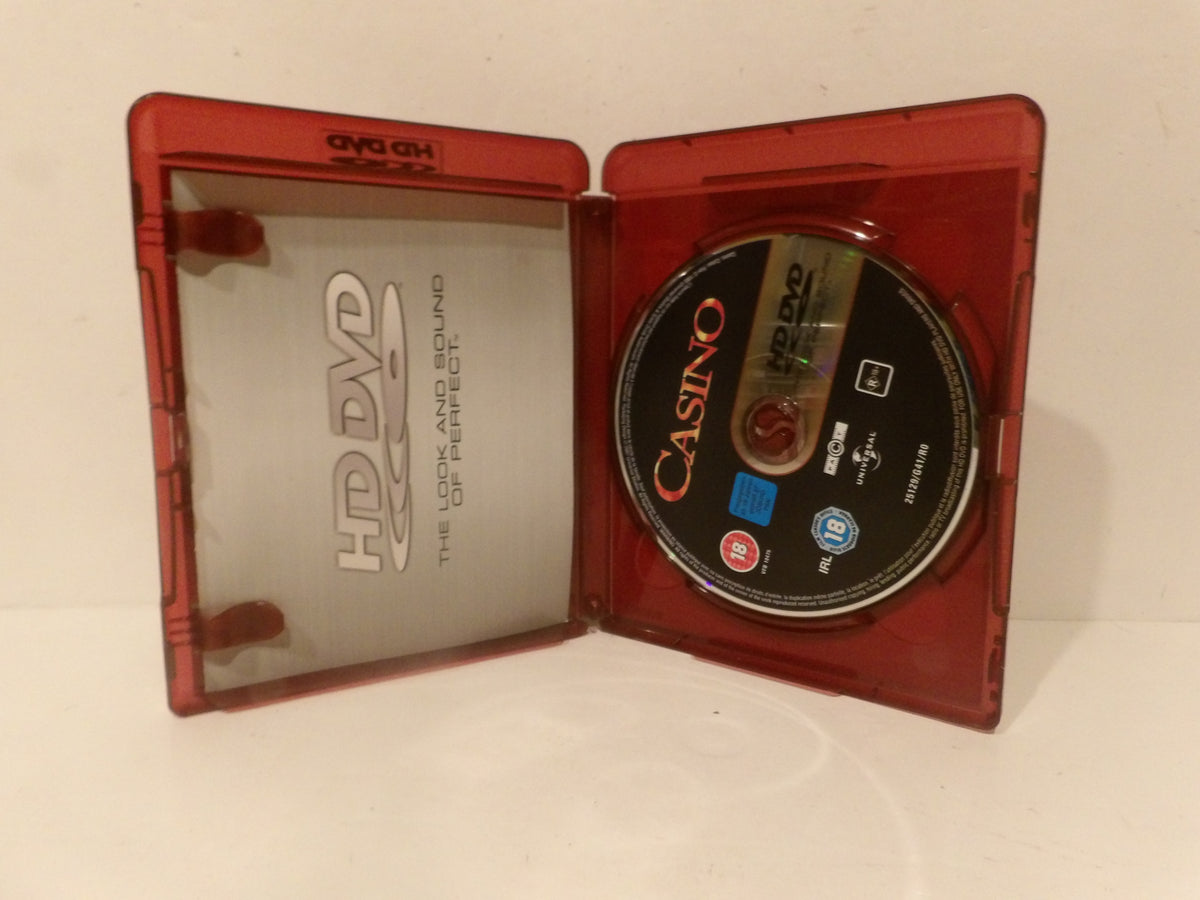 A translucent red plastic HD DVD case shown open, with the inner lid featuring a silver insert and the disc inside displaying a black and red Casino logo.