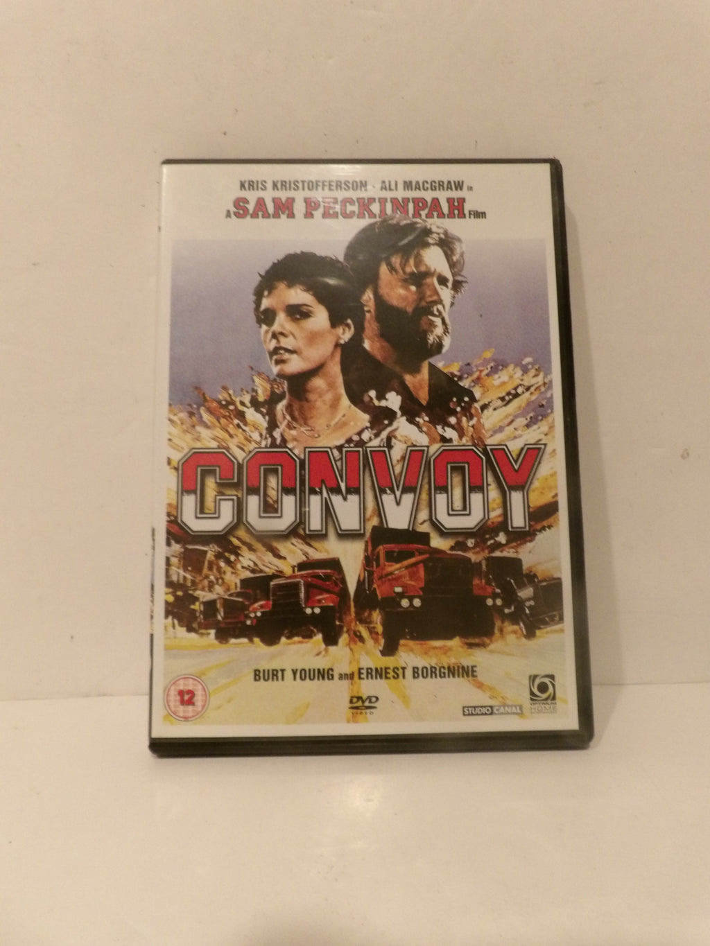 A DVD case for the movie 'Convoy' resting on a plain off-white surface. The cover features a vintage-style illustration of two actors, two trucks, and the title 'CONVOY' in large red letters.