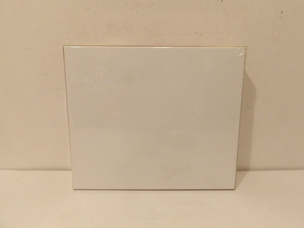 A plain white rectangular box or package standing upright against a light beige wall and surface.