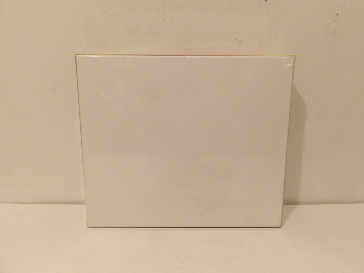 A plain white rectangular box or package standing upright against a light beige wall and surface.