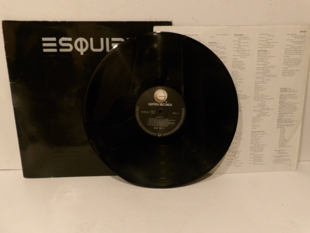 A black vinyl record from Capitol Records leaning against its black sleeve, with the printed inner label visible and a white printed sheet behind it.