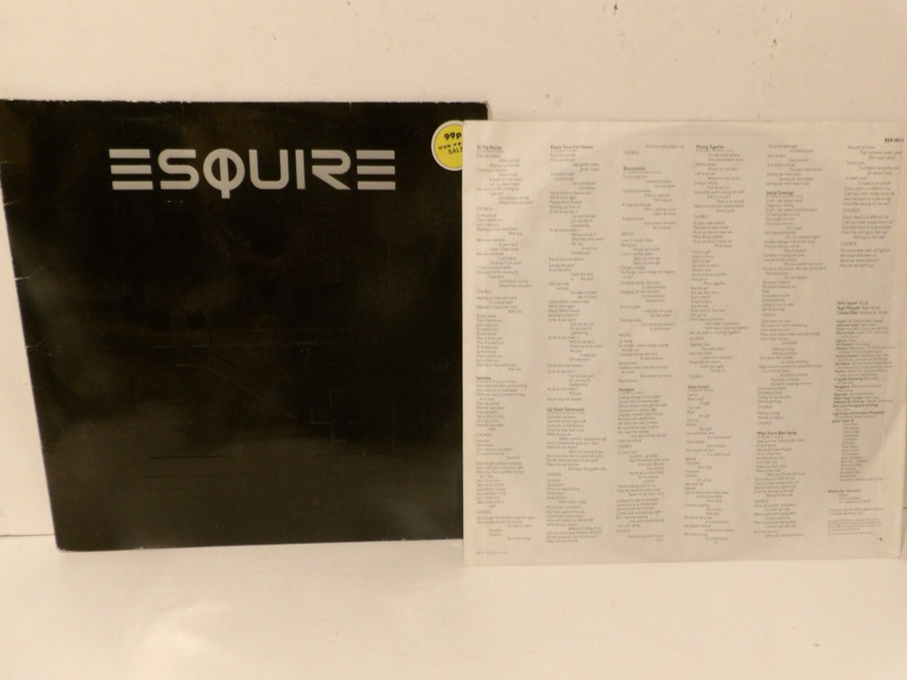 A black Esquire vinyl record sleeve with the word 'ESQUIRE' in white stylized lettering, placed next to a large white printed insert or lyric sheet on a white surface against a white wall.
