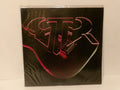 A square black product box or package with a stylized pink and red outlined guitar graphic and large abstract lettering, photographed against a plain light background.