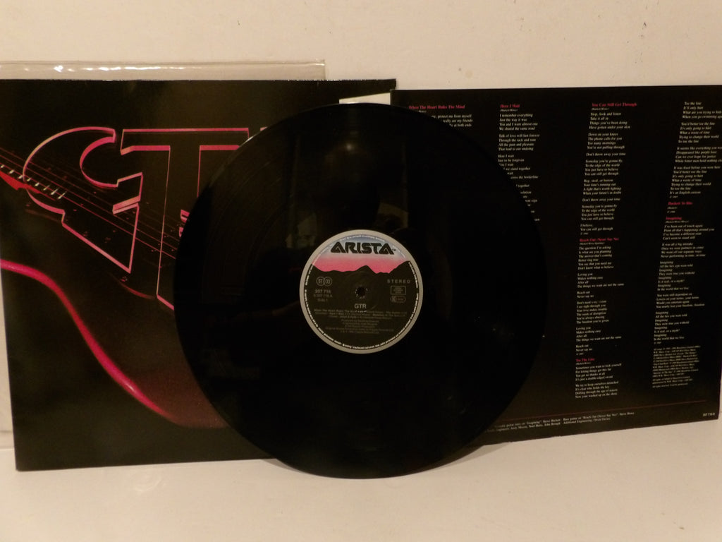 A black vinyl record partially pulled from its sleeve, with the record label reading ARISTA. The album cover is black with pink graphic lines and text tracks visible on the inner sleeve.
