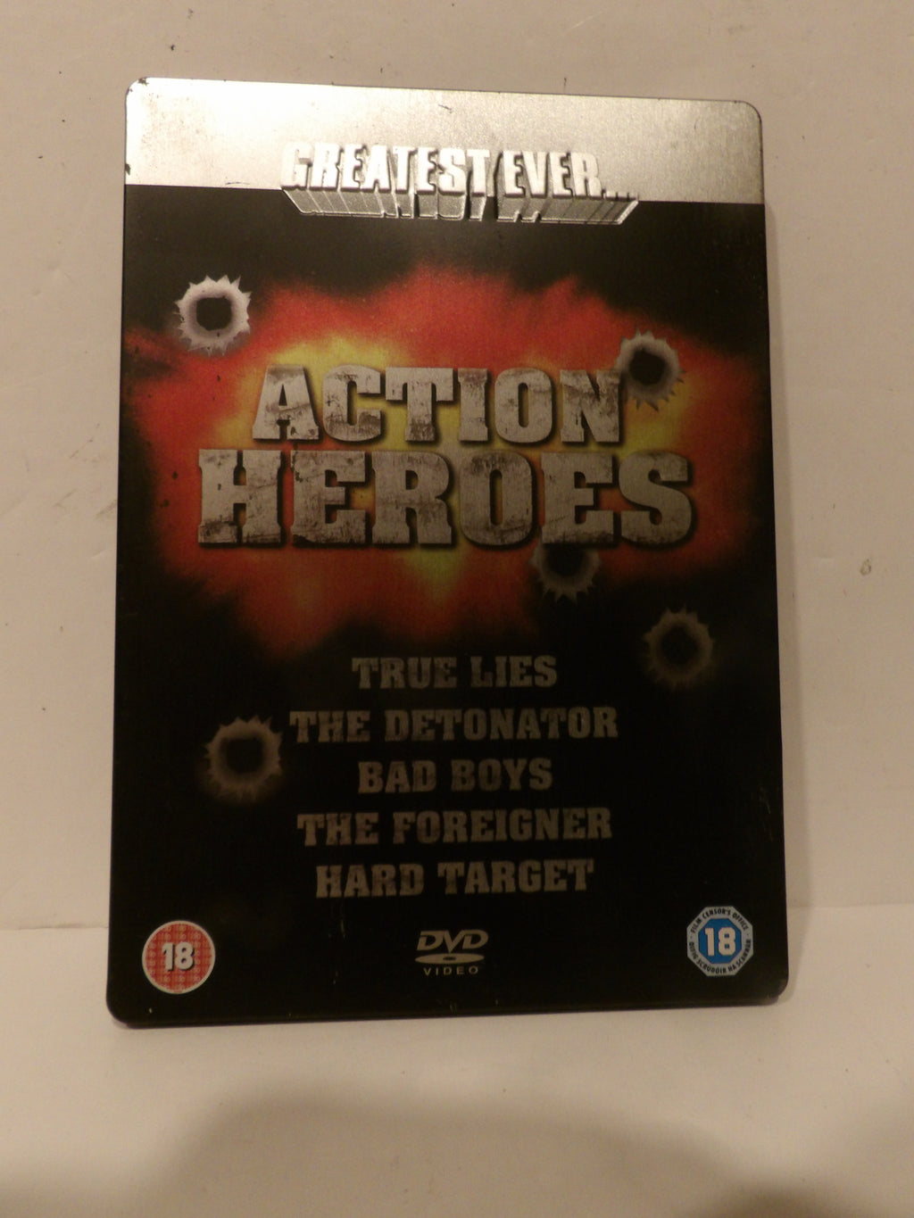DVD cover for the movie 'Action Heroes' featuring a black background with a red and orange explosion graphic, bullet hole details, and a silver metallic top border.