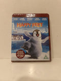 A boxed movie case for Happy Feet, photographed standing upright on a light surface. The front cover shows the penguin character in an icy blue-and-white scene with the title 'HAPPY FEET' in large orange letters.