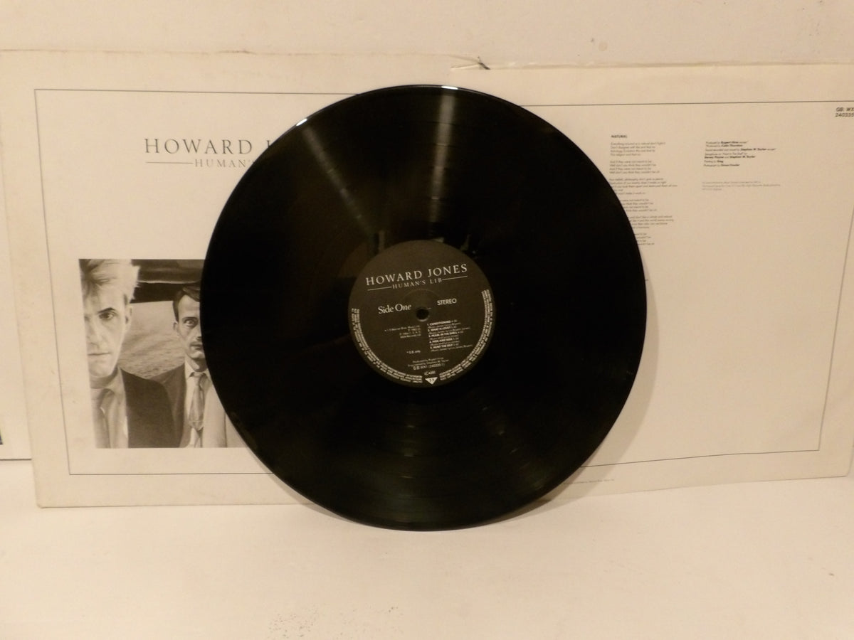A black vinyl record with a Howard Jones label sits in front of its white album sleeve, photographed against a plain light background.