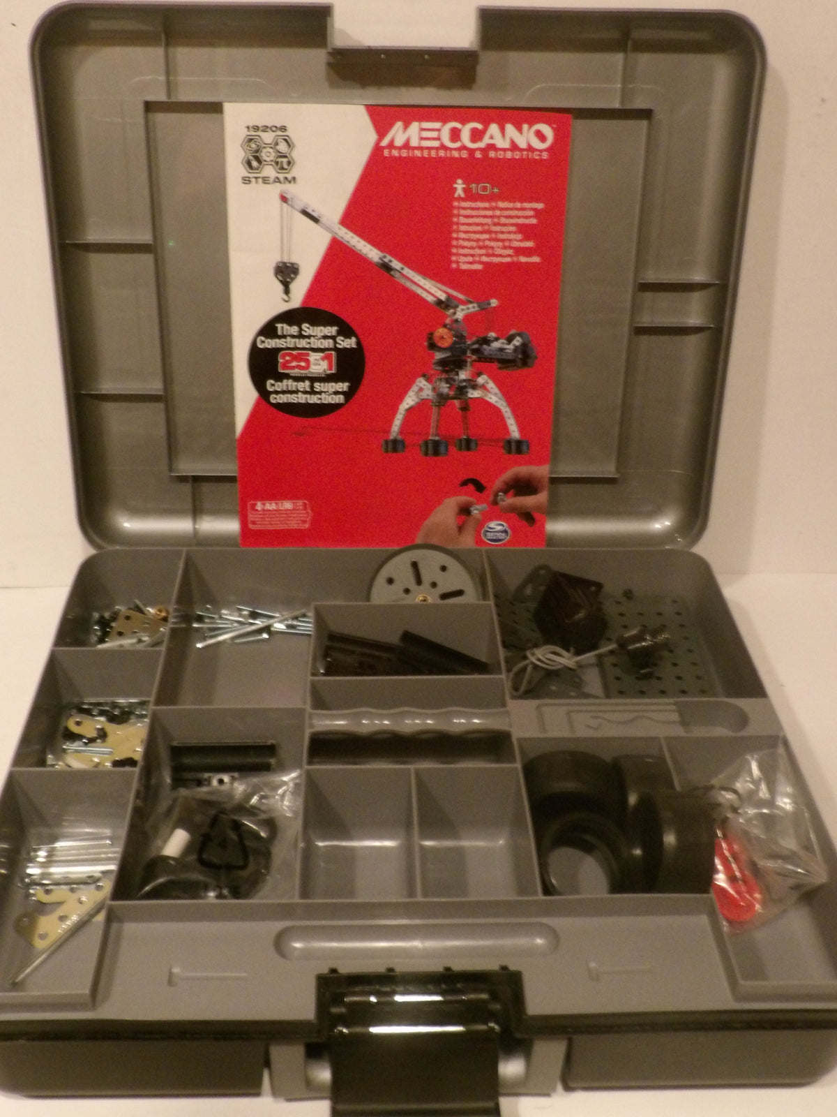 Open Meccano Engineering and Robotics kit storage case showing the gray plastic organizer tray filled with parts and tools, with the red and white Meccano instruction card standing inside the lid.