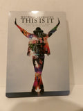 Michael Jackson's 'This Is It' steelbook Blu-ray case standing upright against a light beige wall. The cover features a silver-gray background with a colorful silhouette of Michael Jackson in a rainbow jacket and hat, with the title 'THIS IS IT' in bold black letters at the top.