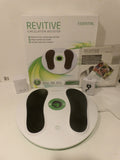 A Revitive Essential Circulation Booster foot massager shown with its retail box, manual, and accessories on a white surface against a white wall.
