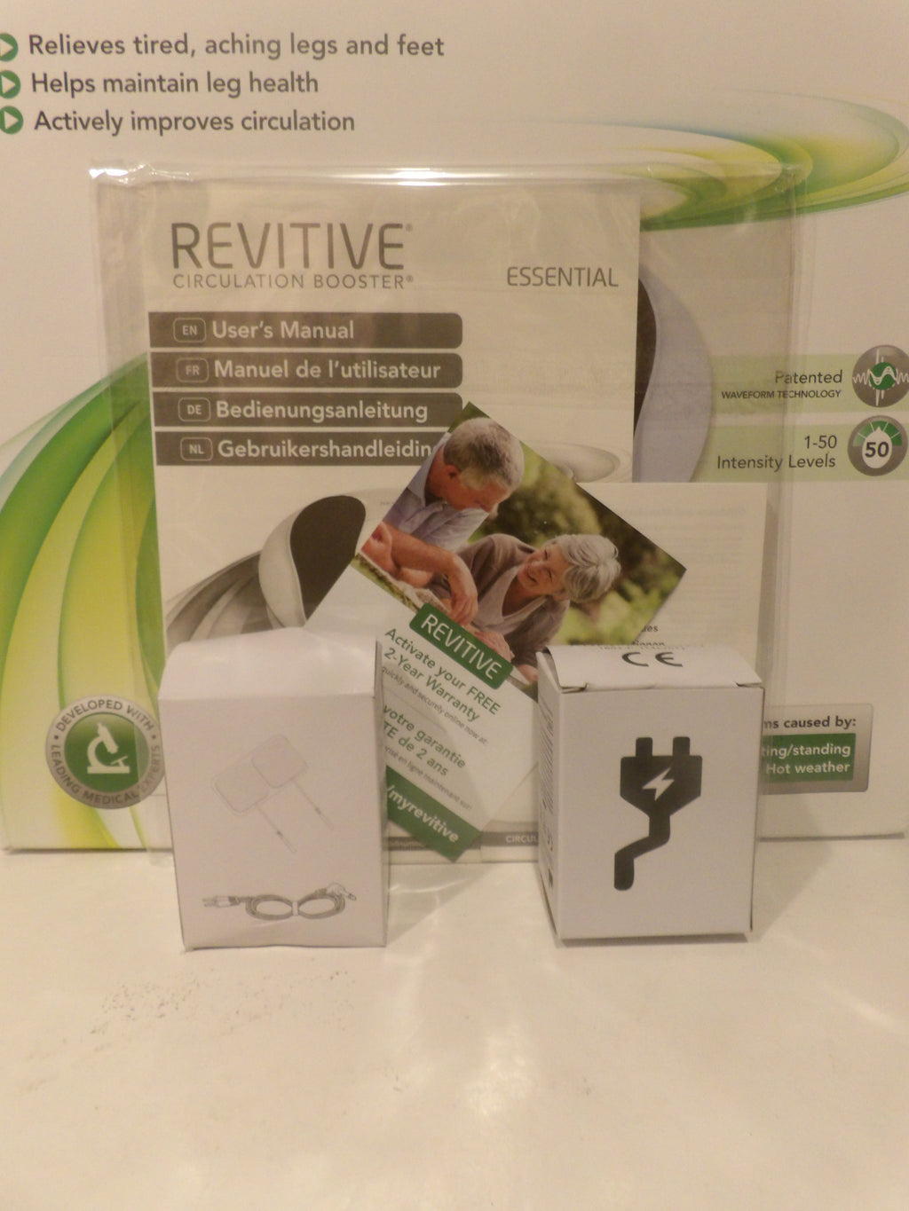 Revitive Circulation Booster Essential kit showing the main product box, user manual, accessories in white boxes, and a power adapter on a white surface.