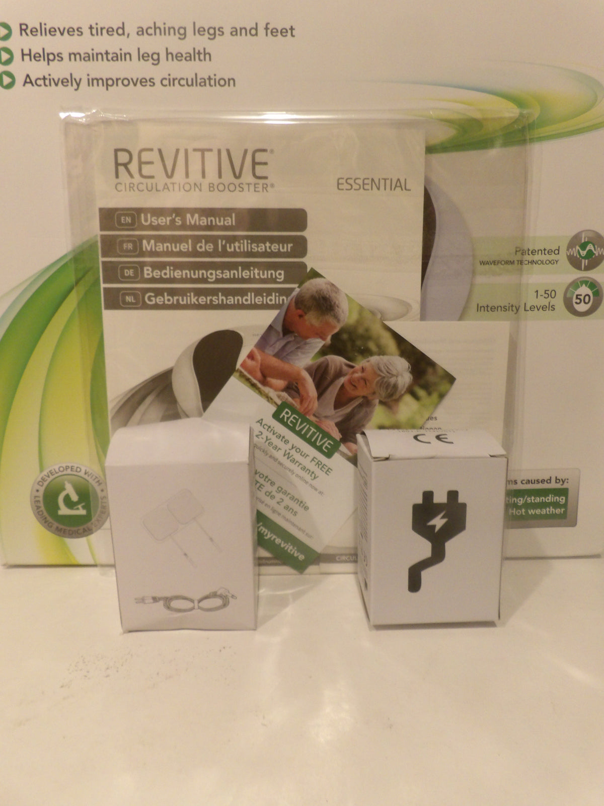 Revitive Circulation Booster Essential kit showing the main product box, user manual, accessories in white boxes, and a power adapter on a white surface.
