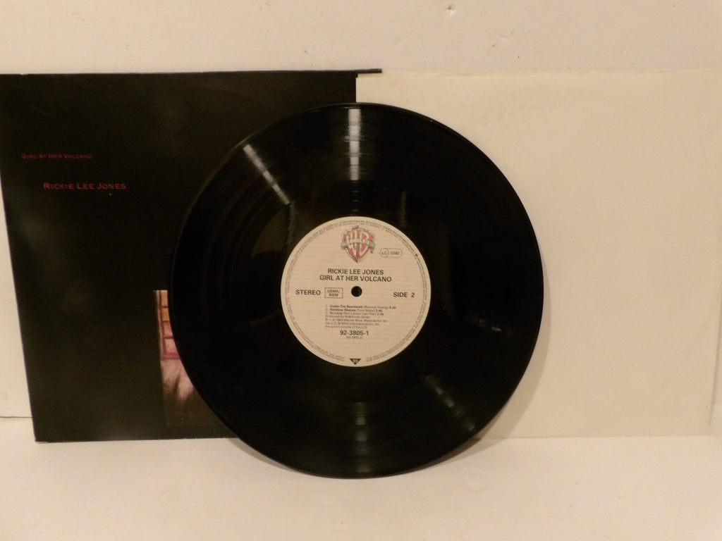 A vinyl record partially pulled from its black album sleeve, photographed against a plain off-white background. The center label shows the Warner Bros.