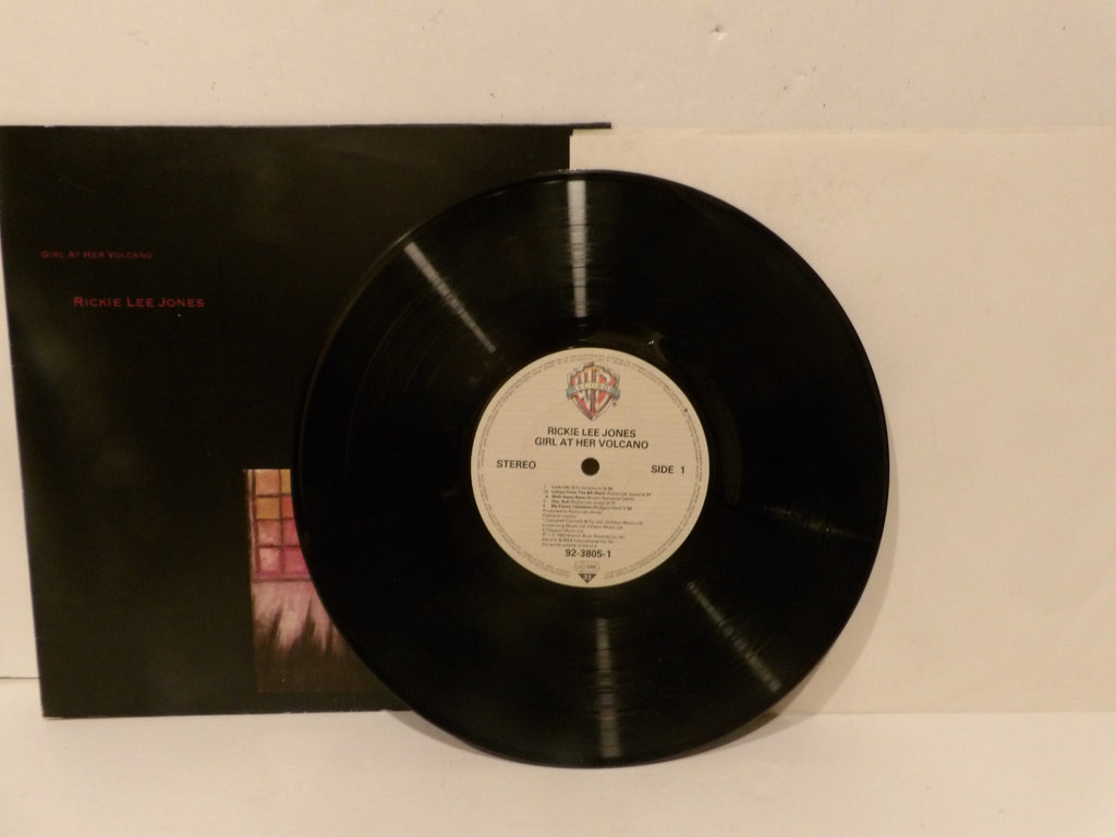 A black vinyl record partially pulled from its black sleeve, showing the center label with the Warner Bros. logo and text for Midge Lee Jones's 'Girl at the Beach'.