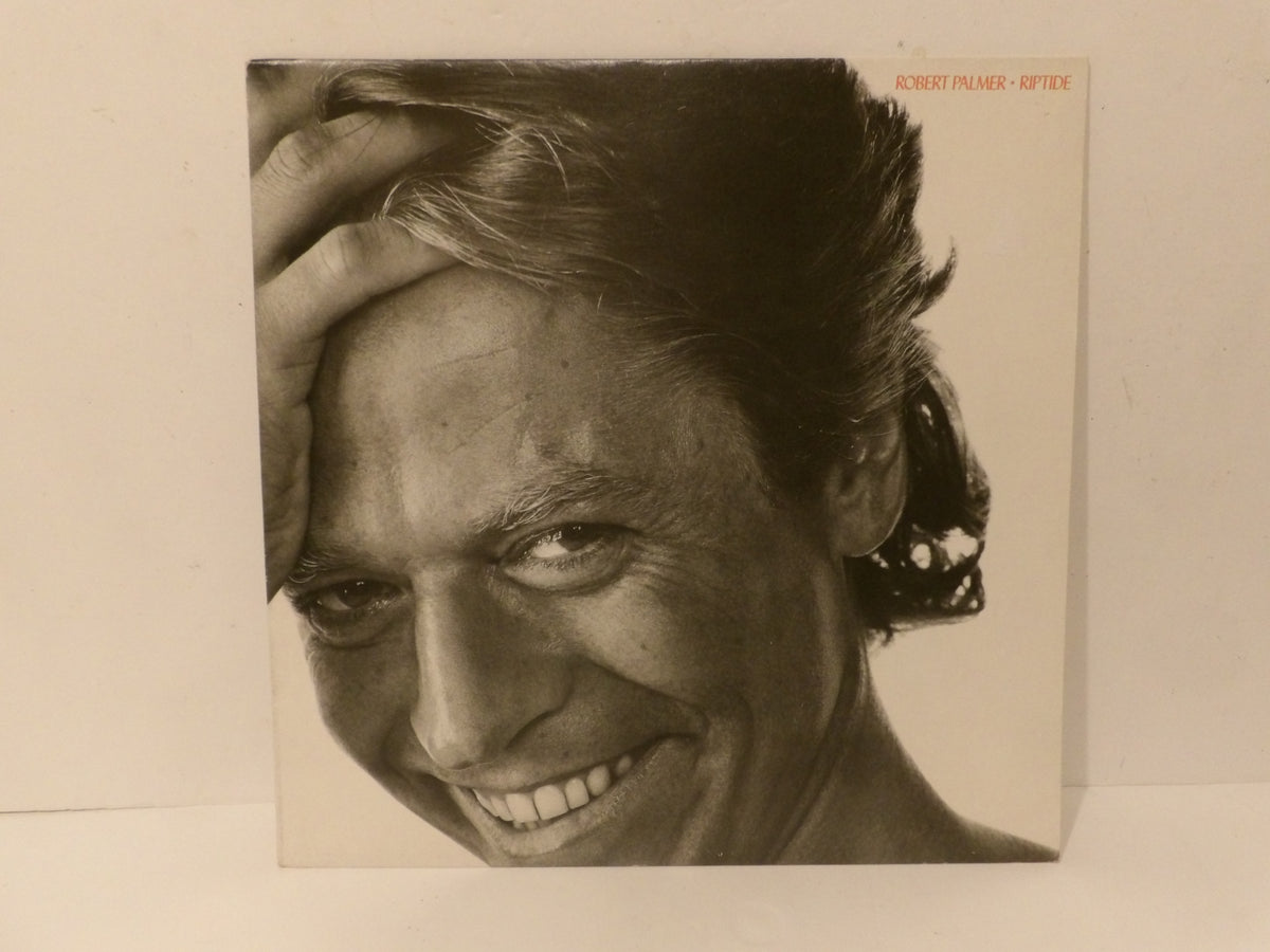 A square album cover featuring a black-and-white close-up portrait of Robert Palmer smiling, with the text 'ROBERT PALMER - SPY' in small orange lettering at the top right, photographed against a plain light background.