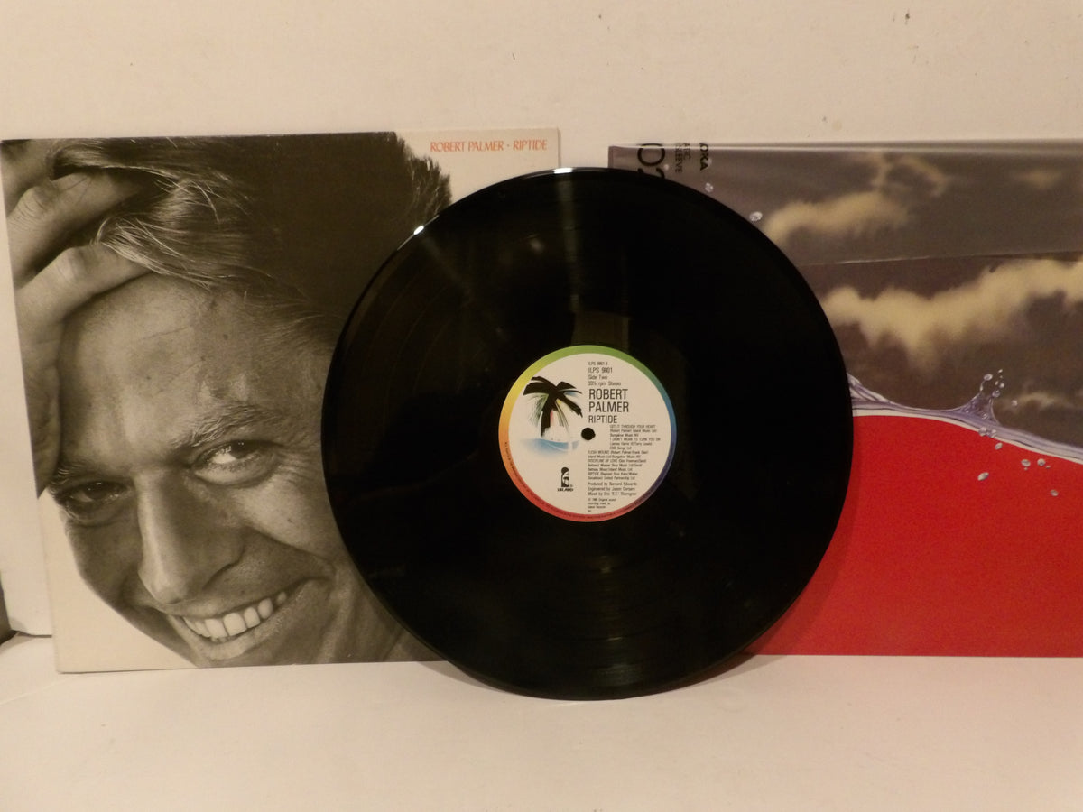 A black vinyl record partially covering its album sleeve, with the sleeve showing a black-and-white portrait on the left and a red-and-white scenic design on the right. The center label of the record is visible.