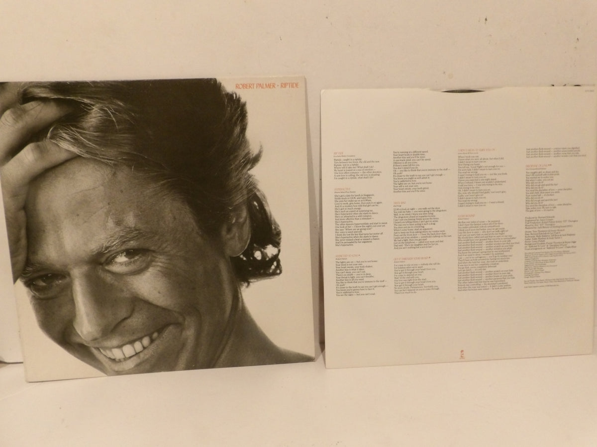 A vinyl record album shown with its front cover featuring a black-and-white portrait of a smiling man, next to the printed inner sleeve with track listings, set against a plain off-white background.