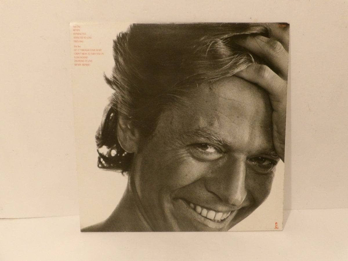 A square album cover featuring a black-and-white close-up portrait of a smiling man with his hand on his hair, photographed against a plain off-white background.