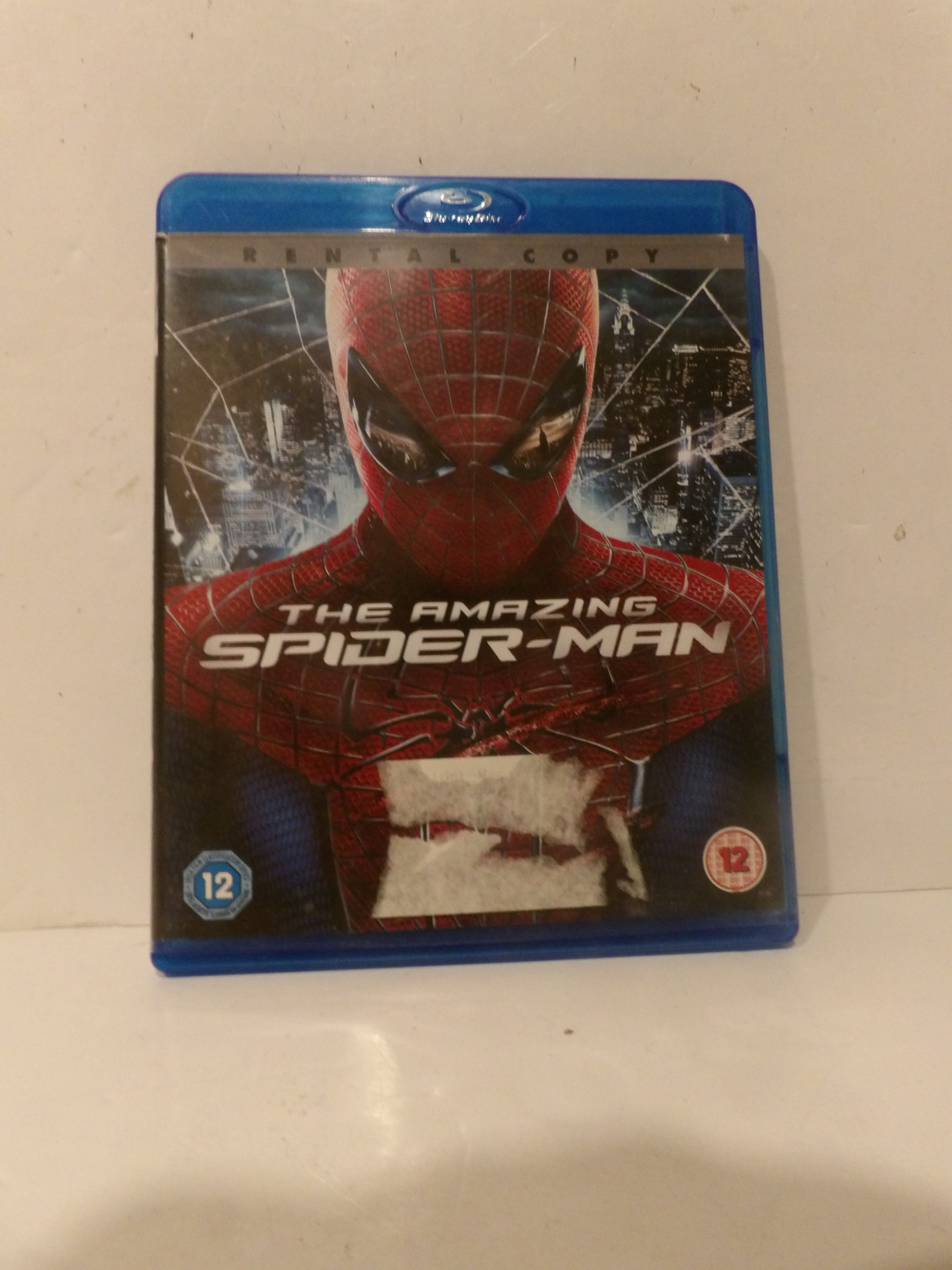 A Blu-ray case of The Amazing Spider-Man 1, featuring Spider-Man on the cover with a blue plastic case border, photographed on a light-colored surface.
