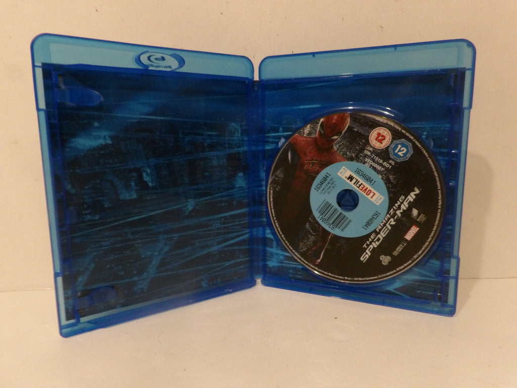 A Blu-ray case opened flat, showing a Spider-Man movie disc inside. The case is translucent blue plastic with a dark cityscape print on the inside cover, and the disc label reads Marvel and Spider-Man.