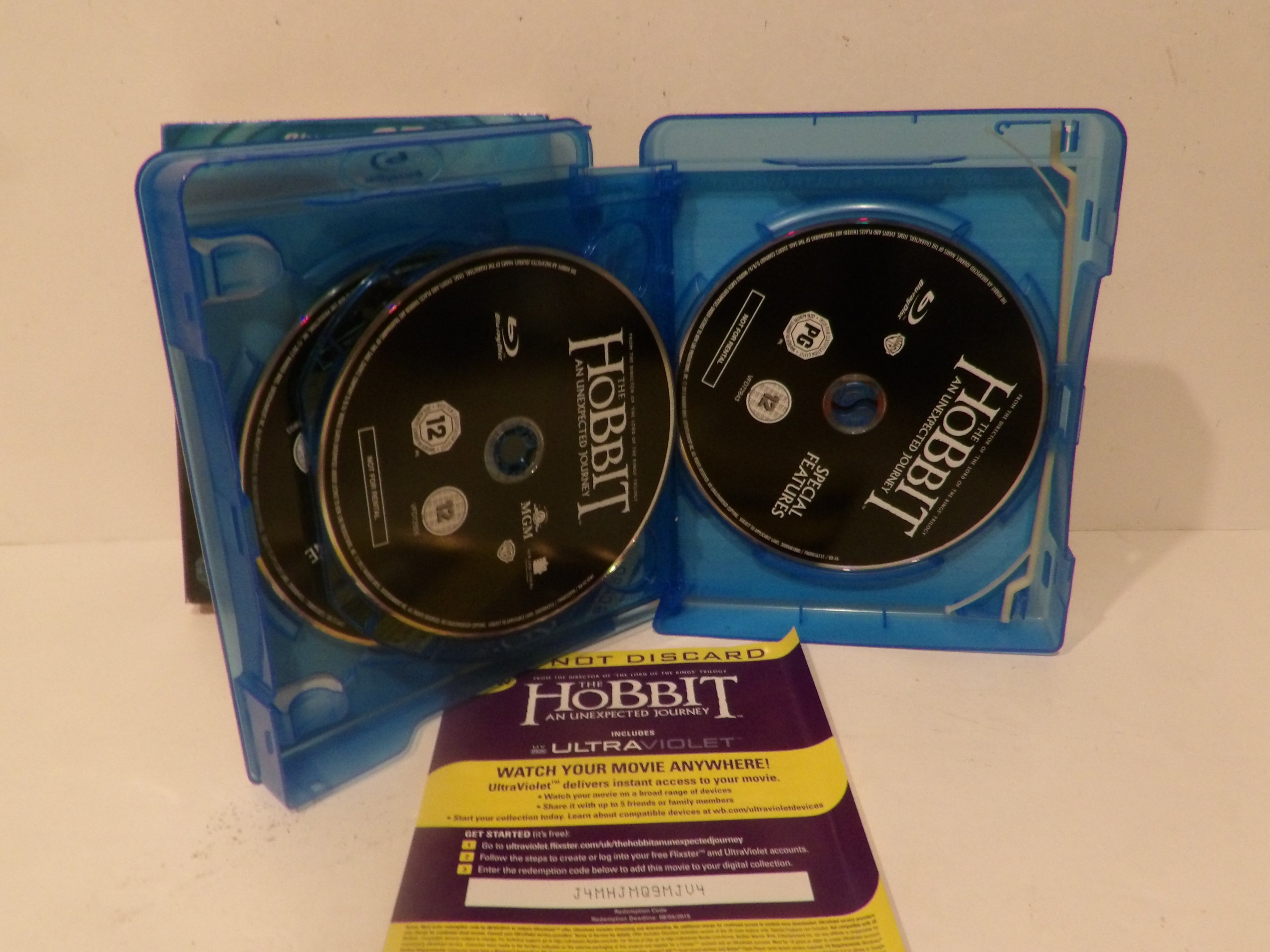 A set of Hobbit: The Desolation of Smaug Ultra HD Blu-ray discs in their blue plastic cases, with a yellow and purple Ultra HD booklet in front on a plain light background.