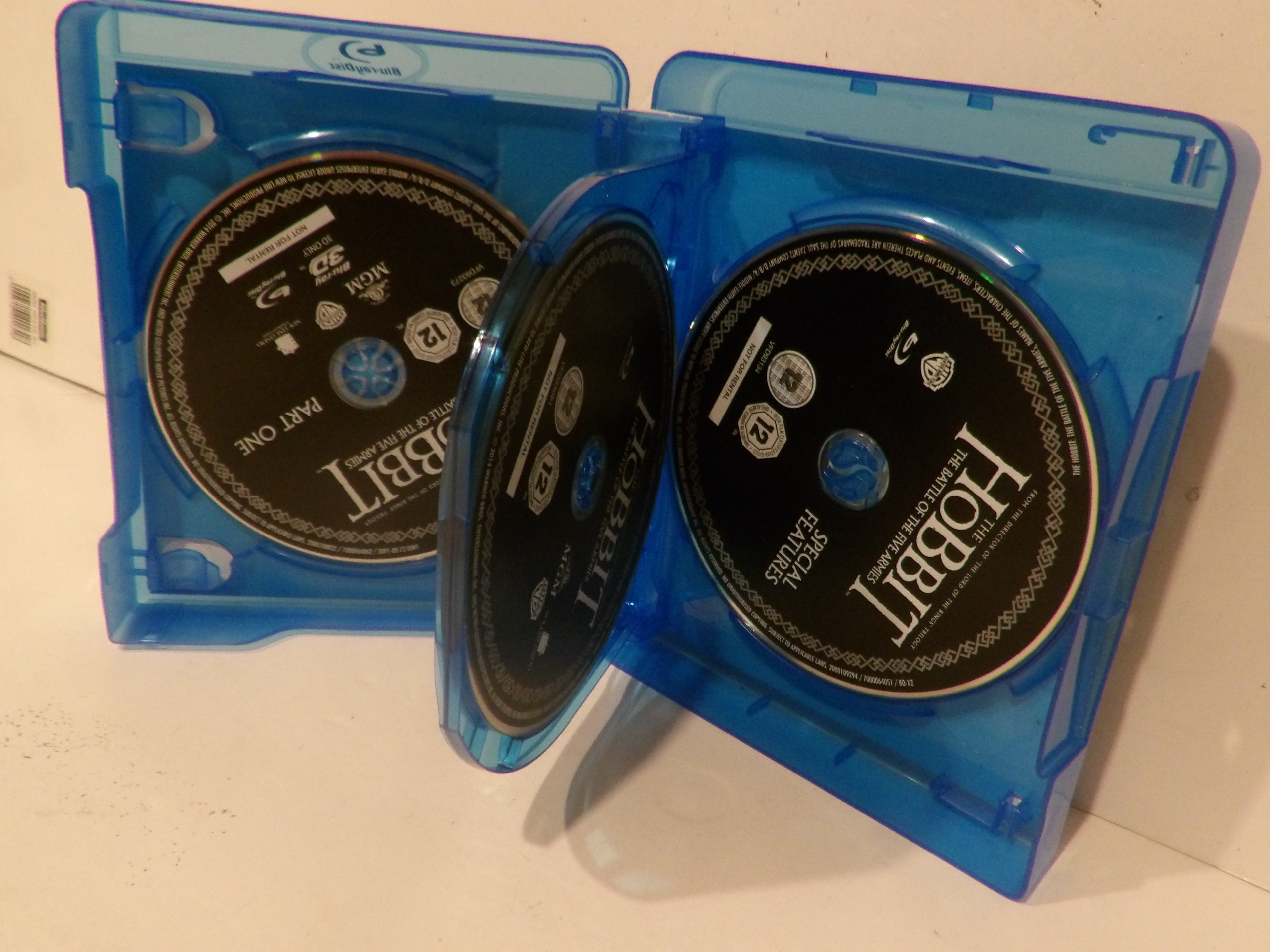 Two blue plastic DVD cases containing Hobbit: The Lord of the Rings movie discs, shown open on a light surface.