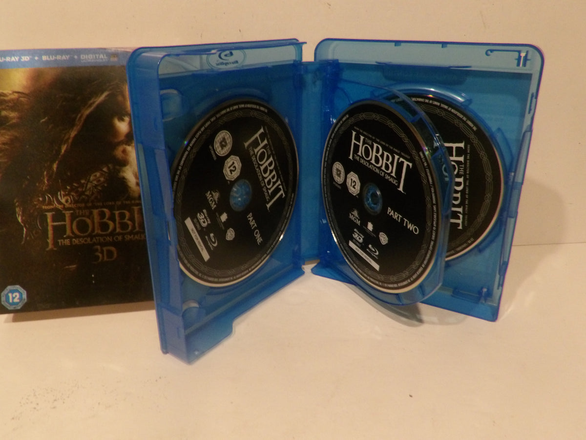 A blue plastic Blu-ray case open to show two Hobbit: The Battle of the Five Kings 3D discs, with the Blu-ray case standing upright and the Blu-ray box partially visible behind it on a light surface.