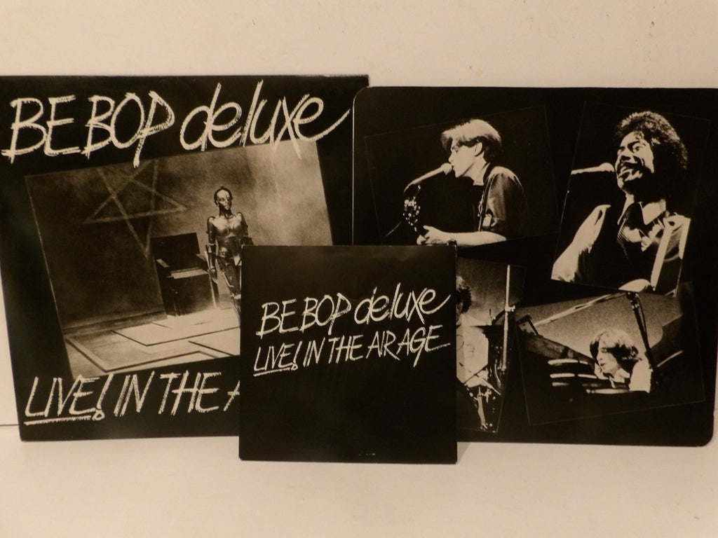 A set of three black square album art prints or sleeves for 'BE BOP deluxe LIVE! IN THE ARAGE', featuring black-and-white photos of a musician performing, displayed against a plain off-white background.