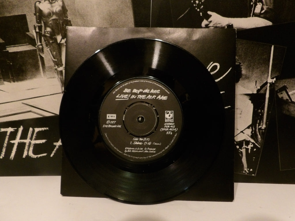 A black vinyl record standing upright in front of its black paper sleeve, with printed album artwork visible behind it. The center label reads 'Be Before Me Live in the Air Ago' and includes the KTX record label logo.